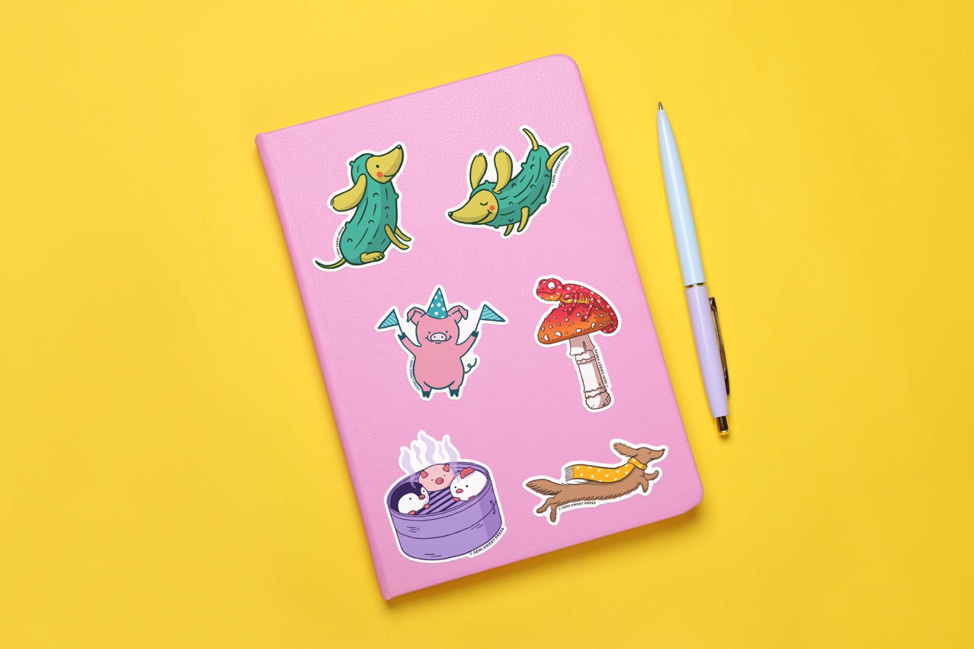 Hand-illustrated stickers on pink notebook on a yellow background